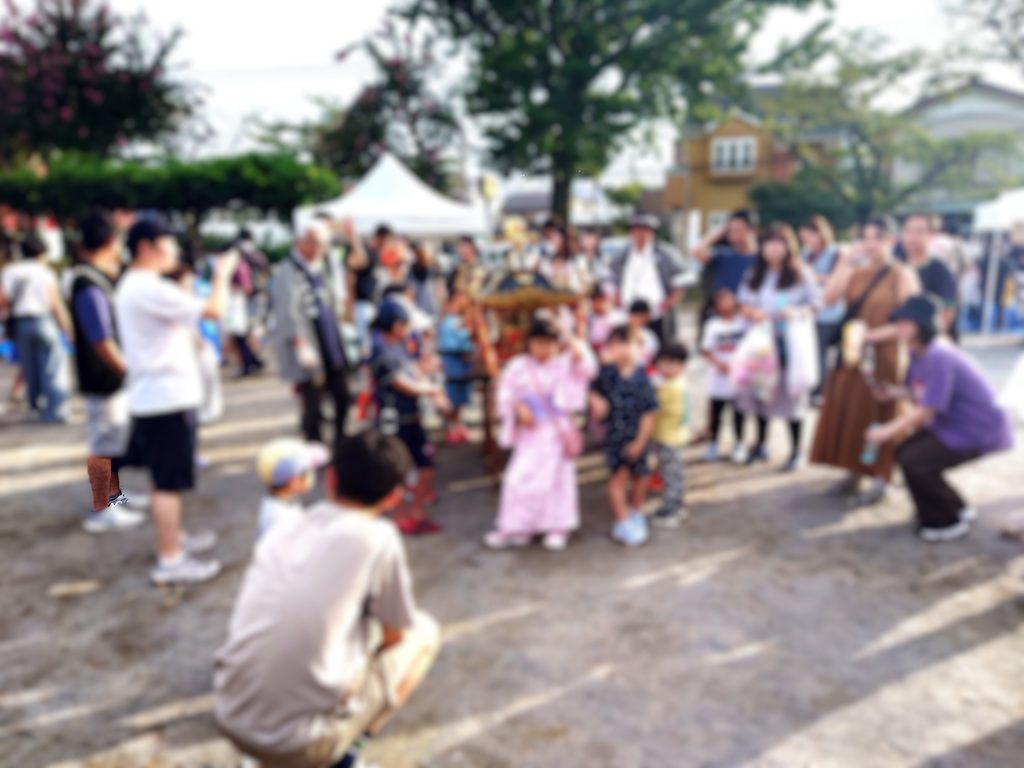 鰭ヶ崎自治会 夏まつりで行われた子どもみこしの様子。お神輿の周りに子どもたちや地域の人たちが集まり、会場がにぎわっている。